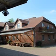 Ferienhof Meyer Ein Backsteingebäude mit Flachdach und Balkonen vor blauem Himmel und bepflastertem Hofweg.
