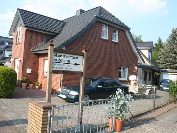 Gäste Appartement im Zentrum Zweistöckiges Backsteinhaus mit Parkplatz und einem Schild "Gäste Appartement im Zentrum" im Vorgarten.