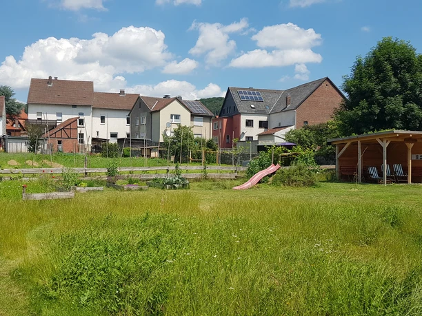 schutzhuette_georgsgarten_ottbergen_2.jpg Eine kleine hölzerne Schutzhütte im Grünen, umgeben von Häusern und einladendem Sonnenschein.