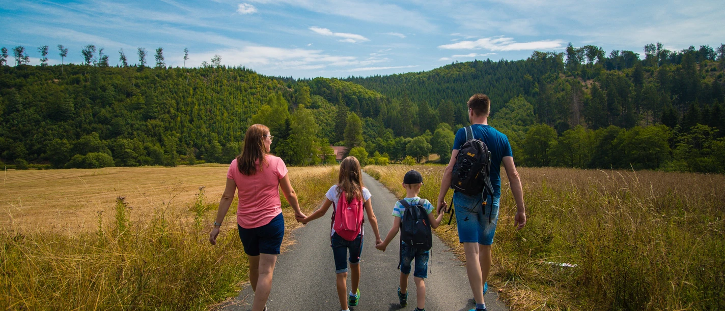 Familie auf der Schützenwiese Eine Familie spaziert auf einem Weg in einer offenen Wiese, umgeben von grünen Wäldern.