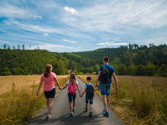 Familie auf der Schützenwiese Eine Familie spaziert auf einem Weg in einer offenen Wiese, umgeben von grünen Wäldern.
