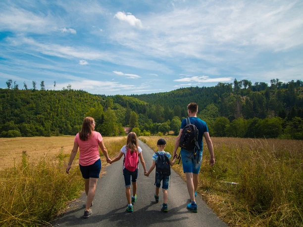 Familie auf der Schützenwiese Eine Familie spaziert auf einem Weg in einer offenen Wiese, umgeben von grünen Wäldern.