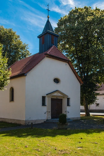 Kapelle in Elisenhof Weiße Kapelle mit rotem Satteldach und kleinem Turm, umgeben von grünen Bäumen im Sommer.