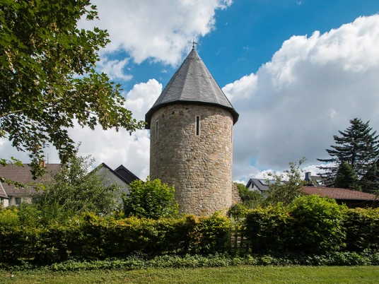 Wehrturm Bad Wünnenberg Wehrturm aus dem Mittelalter in Bad Wünnenberg, umgeben von grüner Vegetation und Wohnhäusern.