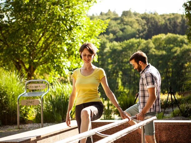 Kneipp Tretbecken an der KneippOase Eine Frau und ein Mann genießen ein Kneipp Tretbecken in grüner, sonniger Umgebung.