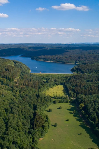 Weitläufige Wälder umgeben den Aabach-Stausee, dessen blaues Wasser die Landschaft prägt.
