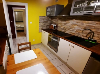 Küche Ferienwohnung Jakobs Helle Küche mit gelben Wänden, Holzarbeitsplatten, Esstisch, Herdplatte und modernen Hängeschränken.