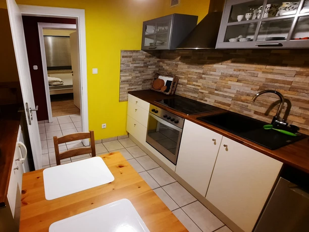 Küche Ferienwohnung Jakobs Helle Küche mit gelben Wänden, Holzarbeitsplatten, Esstisch, Herdplatte und modernen Hängeschränken.