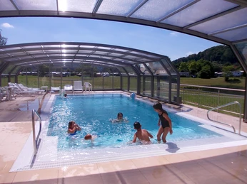 Pool Hallenbad mit klarem Wasser und einziehbarem Dach, Menschen genießen entspannt die sonnige Atmosphäre.