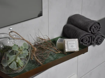 Dekorativ arrangierte Badaccessoires: Sukkulente, Seife und Handtücher auf Tablett in modernem Badezimmer.