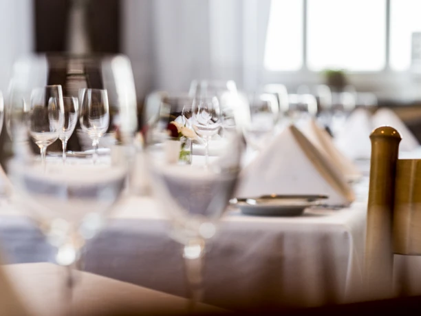 Eleganter, gedeckter Tisch mit Weißwein- und Wassergläsern sowie weißen Stoffservietten.