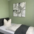 Hotel-und-Restaurant-Borchard-1.jpg Ein Einzelzimmer mit grauem Bett, weißem Kissen und moderner Kunst an einer grünen Wand.