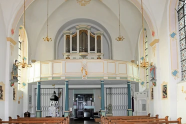 St Vitus innen Innenansicht einer Kirche mit bemalten Wänden, Bänken, Orgel auf dem Balkon, und Leuchtern an der Decke.