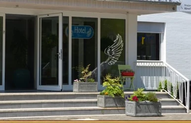 Stadthotel_Espelkamp-Espelkamp-Aussenansicht-693952.jpg Der Eingang zum Stadthotel Espelkamp zeigt Glastüren, Blumenkübel und Sitzgelegenheiten.