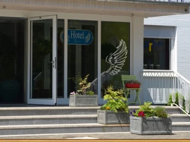 Stadthotel_Espelkamp-Espelkamp-Aussenansicht-693952.jpg Der Eingang zum Stadthotel Espelkamp zeigt Glastüren, Blumenkübel und Sitzgelegenheiten.