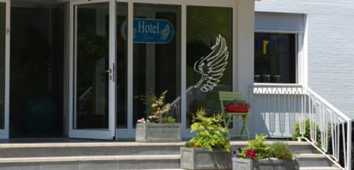 Stadthotel_Espelkamp-Espelkamp-Aussenansicht-693952.jpg Der Eingang zum Stadthotel Espelkamp zeigt Glastüren, Blumenkübel und Sitzgelegenheiten.