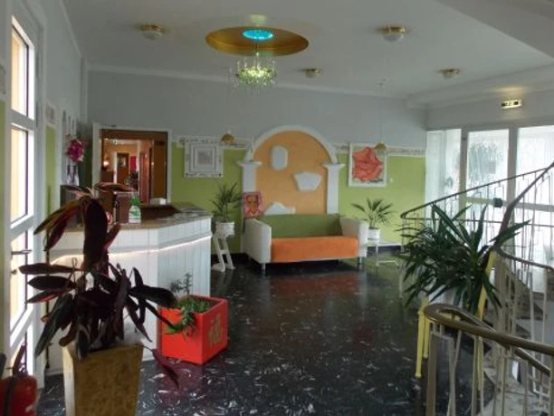 Stadthotel_Espelkamp-Espelkamp-Hotel_Innenbereich-1-693952.jpg Heller Hotel-Innenbereich mit Sitzmöglichkeiten, Pflanzen, dekorativen Elementen und geschwungenem Treppenaufgang.