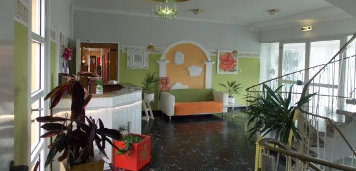 Stadthotel_Espelkamp-Espelkamp-Hotel_Innenbereich-1-693952.jpg Heller Hotel-Innenbereich mit Sitzmöglichkeiten, Pflanzen, dekorativen Elementen und geschwungenem Treppenaufgang.