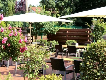 Mittwald Hotel & MCM Restaurant Außenbereich des Mittwald Hotels mit Sitzgelegenheiten, umgeben von grünen Pflanzen und Blumen.