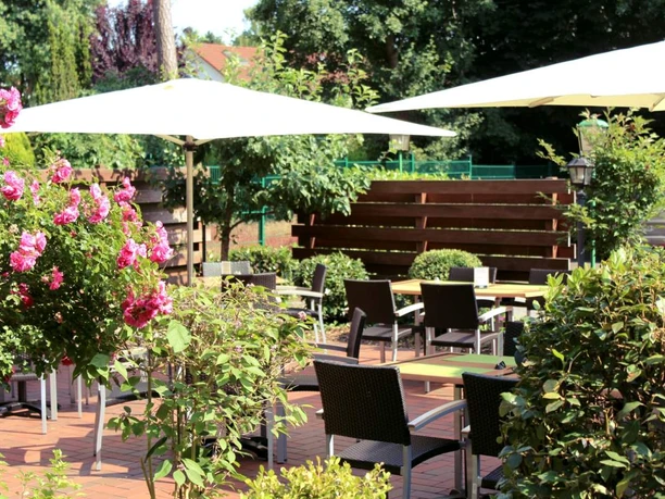 Mittwald Hotel & MCM Restaurant Außenbereich des Mittwald Hotels mit Sitzgelegenheiten, umgeben von grünen Pflanzen und Blumen.