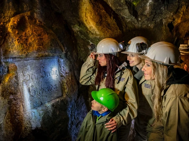 Visitors in protective clothing and helmets explore the historic silver mine in Freiberg.