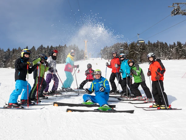 Winterspass Gruppe von Skifahrern auf einer Skipiste, darunter ein fröhlicher Skilehrer.
