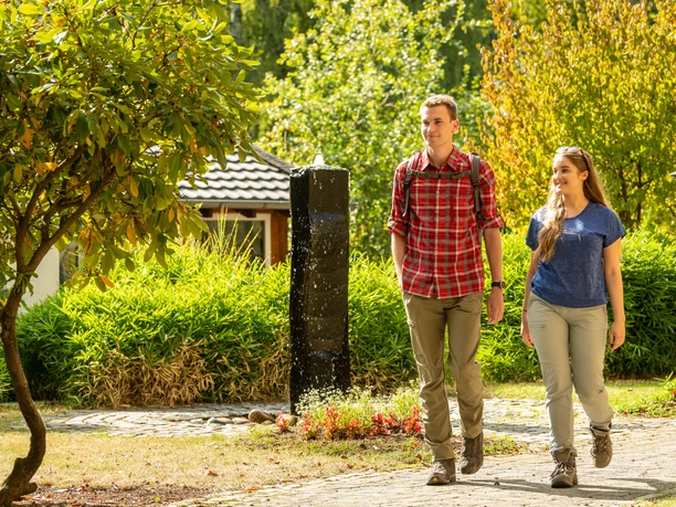 Seelscheid <p>Ein junges Paar spaziert bei sonnigem Wetter durch einen grünen, gepflegten Park.</p>