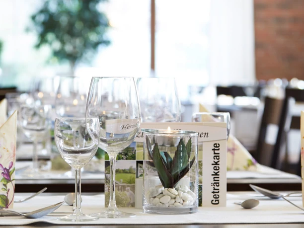 Hotel-Bad-Griepshop Festlich gedeckter Tisch mit Weingläsern, gefalteten Servietten und kleiner Pflanze in hellem Raum.