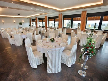 Hotel Wiehentherme Großer, eleganter Bankettsaal mit runden, weiß eingedeckten Tischen und großen Fenstern.