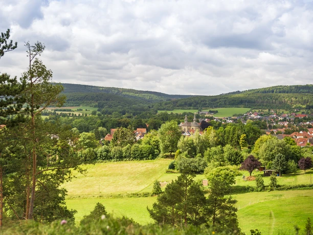 Blick aufs Schloss Willebadessen Blick auf Schloss Willebadessen inmitten grüner Landschaft, umgeben von bewaldeten Hügeln und Feldern.