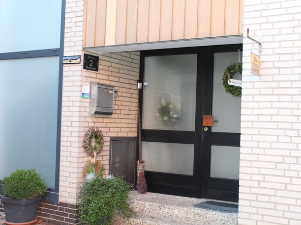 Entrance area of a modern guesthouse with glass front door and discreetly decorated Christmas entrance.