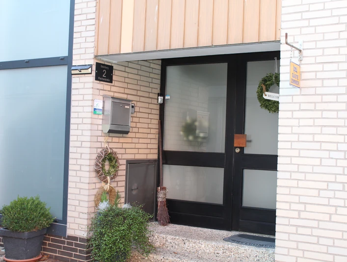 Eingangsbereich einer modernen Pension mit gläserner Haustür und dezent weihnachtlich dekoriertem Eingang.Entrance area of a modern guesthouse with glass front door and discreetly decorated Christmas entrance.Indgangsparti til et moderne gæstehus med glasdør og diskret juleudsmykket indgang.Entree van een modern pension met glazen voordeur en discreet versierde kerstingang.