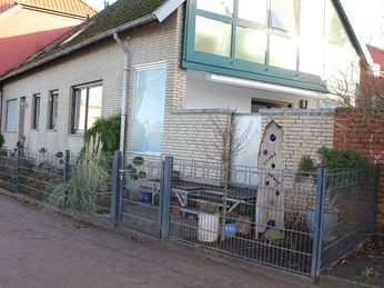 Ein Eckhaus mit hellem Backstein und großzügigen Fenstern, eingezäunt von einem Metallzaun, steht an einer ruhigen Straße.A corner house with light-colored brick and large windows, enclosed by a metal fence, stands on a quiet street.Et hjørnehus med lyse mursten og store vinduer, omgivet af et metalhegn, ligger på en stille gade.Een hoekhuis met lichtgekleurde bakstenen en grote ramen, omsloten door een metalen hek, staat in een rustige straat.