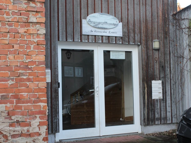 Entrance to a vacation apartment with wooden façade, right-hand brick wall and double glass door.