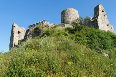 Burgruine Desenberg Ruine der mittelalterlichen Burg auf einem Hügel, umgeben von grüner Vegetation und blauem Himmel.