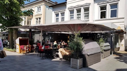 Cult3.jpg Zu sehen ist die Terrasse des Cults an einem sonnigen Tag. Die Menschen sitzen draußen, genießen ihr Getränk und schlemmen köstliche Leckereien.