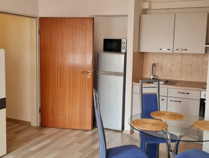 Wohnküche Offene Wohnküche mit Esstisch, Stühlen, Kühlschrank, Mikrowelle, Schränken und Dekoration.