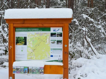 Ein verschneiter Wanderwegweiser im Furlbachtal in einem winterlichen Wald bei Schloss Holte-Stukenbrock.