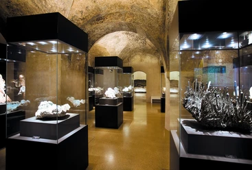 terra mineralia Mineralienausstellung in einem Raum mit gewölbten Steinwänden und beleuchteten Vitrinen.