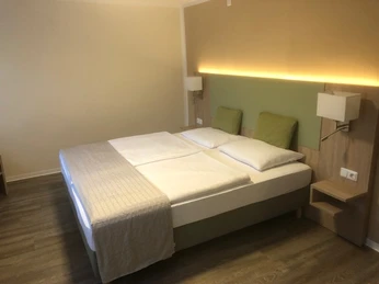 Weiteres Zimmer Ein Doppelbett mit hellem Holzrahmen, zwei Wandlampen und modernen Kopfteilleuchten in einem ruhigen Zimmer.