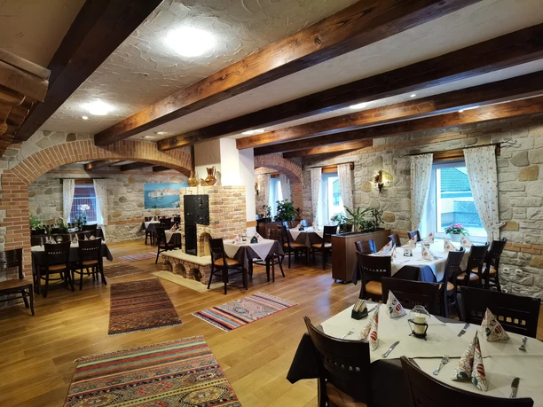 Dubrovnik Ein rustikales Restaurant mit Holzbalkendecke und Steinwänden; bunt gemusterte Teppiche zieren den Boden.