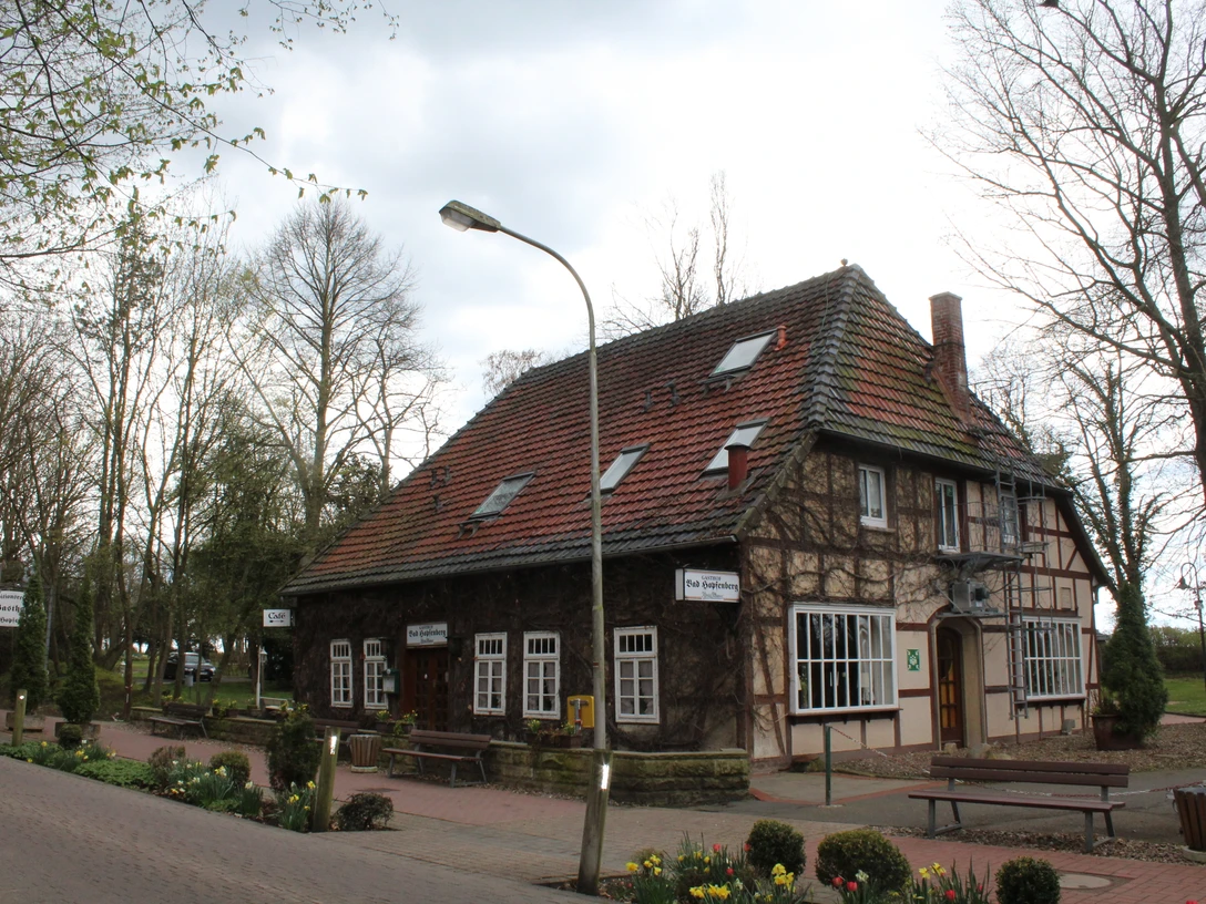 Gasthof Bad Hopfenberg Historischer Gasthof mit rotem Ziegeldach und Fachwerkdetails, umgeben von Bäumen und Blumenbeeten.