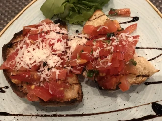 Bruschetta Zwei Scheiben geröstetes Brot, üppig mit frischen, gehackten Tomaten und geriebenem Käse belegt.
