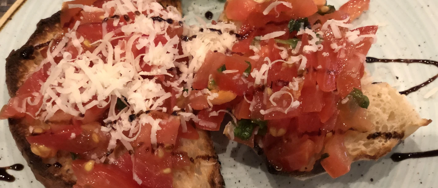 Bruschetta Zwei Scheiben geröstetes Brot, üppig mit frischen, gehackten Tomaten und geriebenem Käse belegt.