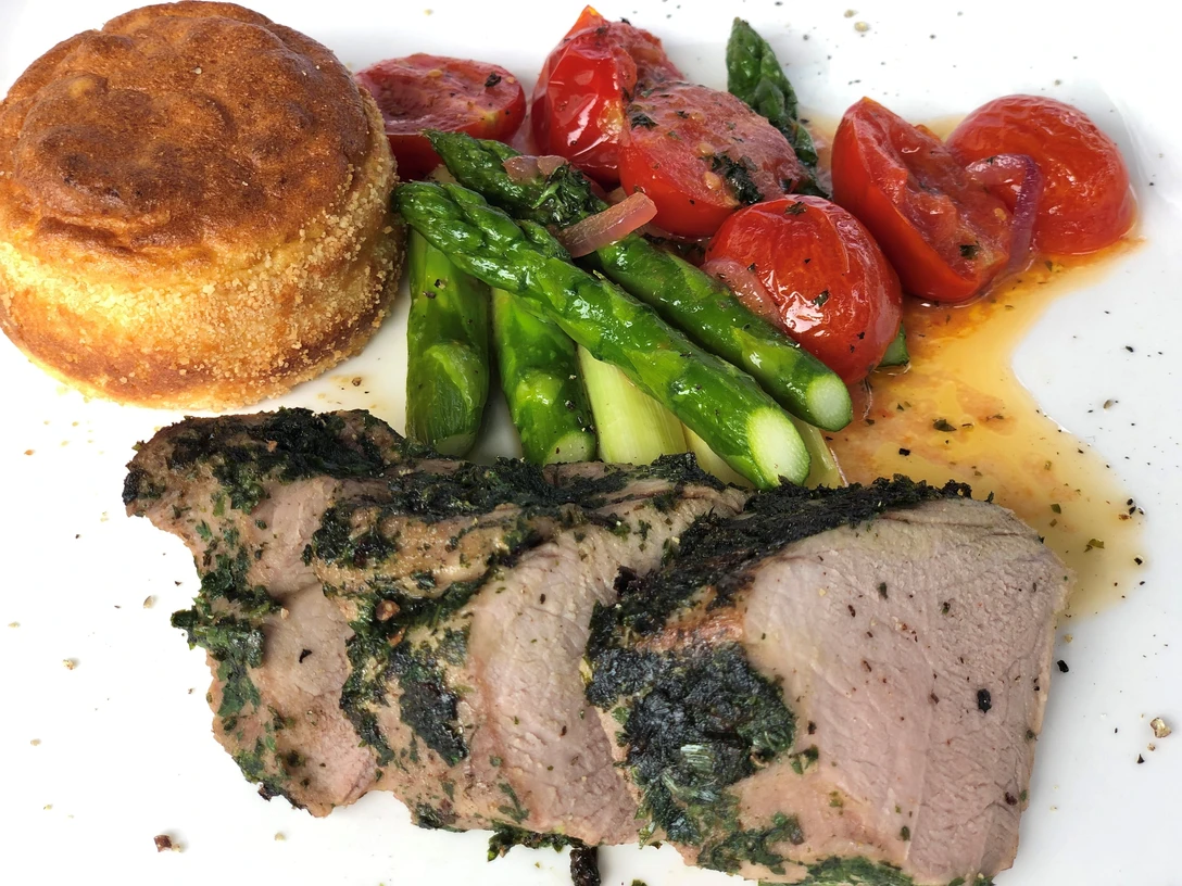 Schweinefilet Ein köstliches Gericht aus saftigem Schweinefilet, umgeben von grünem Spargel und Kirschtomaten.