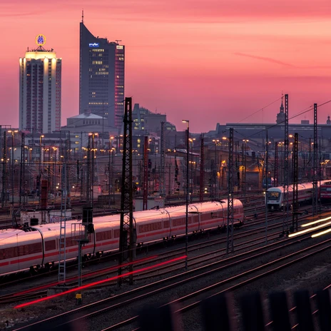 Trains arrive at Leipzig Central Station, in the background the Krochhochhaus, the New Town Hall and the City-Hochhaus at sunset