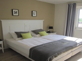 Landhotel-zum-gruenen-Kranze_1.jpg Modern eingerichtetes Hotelzimmer mit zwei Einzelbetten, stilvollen Nachttischen und großem Fenster.