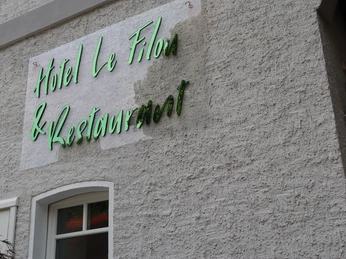 Hotel Filou Hotel Le Filou mit grünem Schriftzug auf rauer, hellgrauer Wand oberhalb eines Fensters.