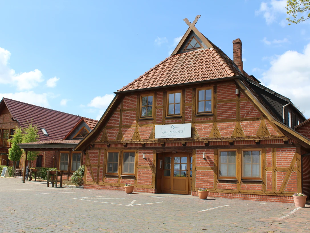 Das Bild zeigt ein traditionelles Fachwerkhaus mit ziegelfarbenen Akzenten und einem gepflegten Hof.