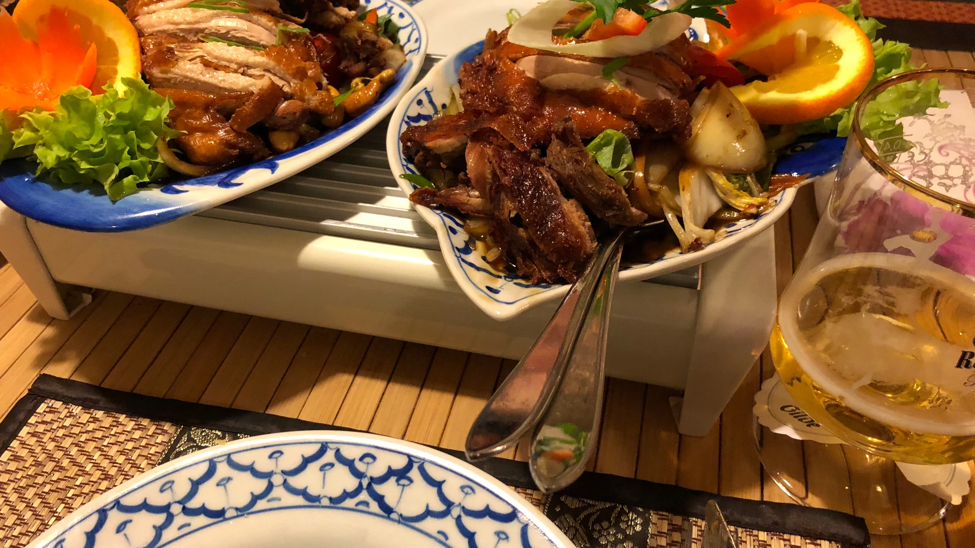 Knusprig gebratenes Entengericht auf Porzellanteller mit frischen Orangenscheiben und Gemüsebeilage.
